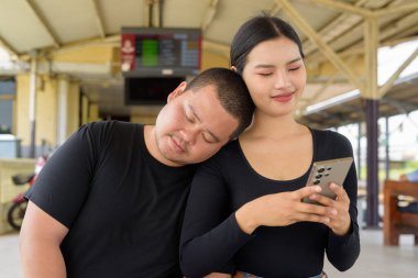 Genç Asyalı çift tren istasyonunda beraberler.