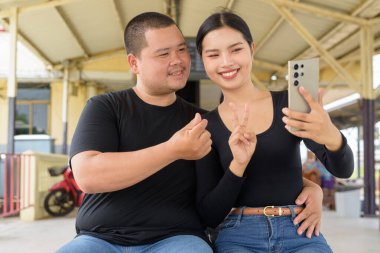 Genç Asyalı çift tren istasyonunda beraberler.