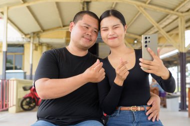 Genç Asyalı çift tren istasyonunda beraberler.