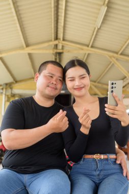 Genç Asyalı çift tren istasyonunda beraberler.