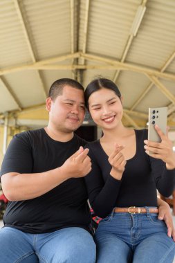 Genç Asyalı çift tren istasyonunda beraberler.