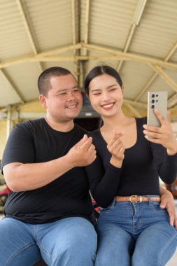 Genç Asyalı çift tren istasyonunda beraberler.