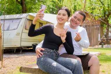 Kamp alanında karavan arabalarıyla kamp yapan Asyalı çift.