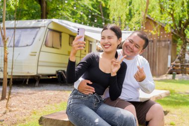 Kamp alanında karavan arabalarıyla kamp yapan Asyalı çift.