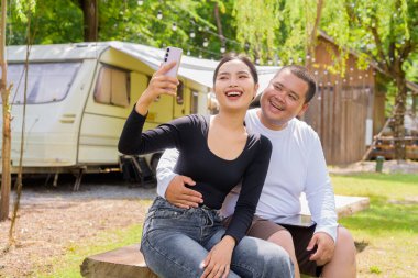 Kamp alanında karavan arabalarıyla kamp yapan Asyalı çift.