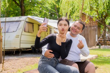 Kamp alanında karavan arabalarıyla kamp yapan Asyalı çift.