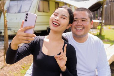 Kamp alanında karavan arabalarıyla kamp yapan Asyalı çift.