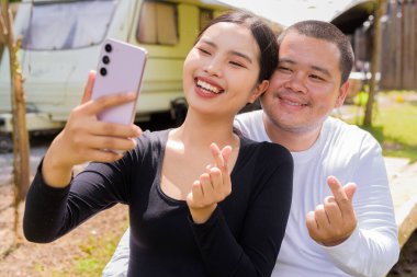 Kamp alanında karavan arabalarıyla kamp yapan Asyalı çift.