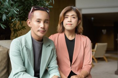 Asyalı transseksüel kadın ve kafede uzaktan çalışan ikili olmayan iş arkadaşları.