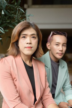 Asyalı transseksüel kadın ve kafede uzaktan çalışan ikili olmayan iş arkadaşları.