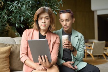 Asyalı transseksüel kadın ve kafede uzaktan çalışan ikili olmayan iş arkadaşları.