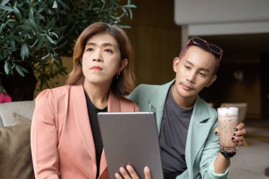 Asyalı transseksüel kadın ve kafede uzaktan çalışan ikili olmayan iş arkadaşları.