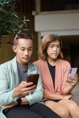 Asyalı transseksüel kadın ve kafede uzaktan çalışan ikili olmayan iş arkadaşları.