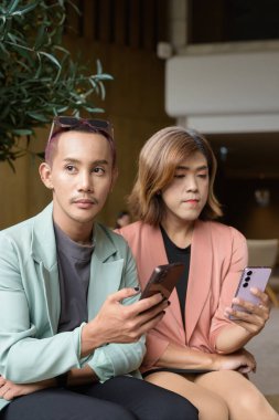 Asyalı transseksüel kadın ve kafede uzaktan çalışan ikili olmayan iş arkadaşları.