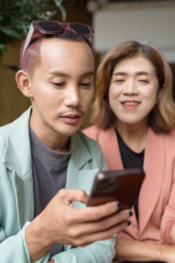 Asyalı transseksüel kadın ve kafede uzaktan çalışan ikili olmayan iş arkadaşları.