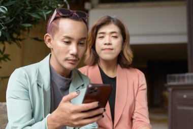 Asyalı transseksüel kadın ve kafede uzaktan çalışan ikili olmayan iş arkadaşları.