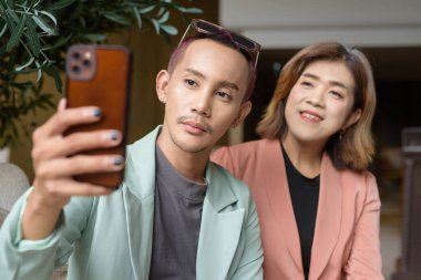 Asyalı transseksüel kadın ve kafede uzaktan çalışan ikili olmayan iş arkadaşları.