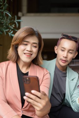 Asyalı transseksüel kadın ve kafede uzaktan çalışan ikili olmayan iş arkadaşları.