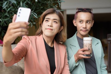 Asyalı transseksüel kadın ve kafede uzaktan çalışan ikili olmayan iş arkadaşları.