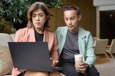 Asyalı transseksüel kadın ve kafede uzaktan çalışan ikili olmayan iş arkadaşları.