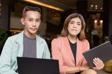 Asyalı transseksüel kadın ve kafede uzaktan çalışan ikili olmayan iş arkadaşları.