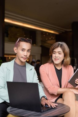 Asyalı transseksüel kadın ve kafede uzaktan çalışan ikili olmayan iş arkadaşları.