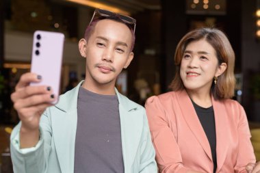 Asyalı transseksüel kadın ve kafede uzaktan çalışan ikili olmayan iş arkadaşları.