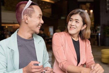 Asyalı transseksüel kadın ve kafede uzaktan çalışan ikili olmayan iş arkadaşları.