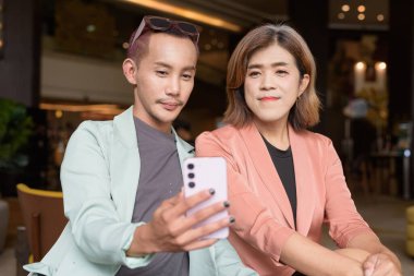 Asyalı transseksüel kadın ve kafede uzaktan çalışan ikili olmayan iş arkadaşları.