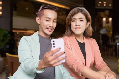 Asyalı transseksüel kadın ve kafede uzaktan çalışan ikili olmayan iş arkadaşları.