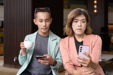 Asyalı transseksüel kadın ve kafede uzaktan çalışan ikili olmayan iş arkadaşları.