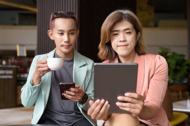 Asyalı transseksüel kadın ve kafede uzaktan çalışan ikili olmayan iş arkadaşları.