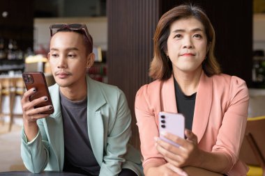 Asyalı transseksüel kadın ve kafede uzaktan çalışan ikili olmayan iş arkadaşları.