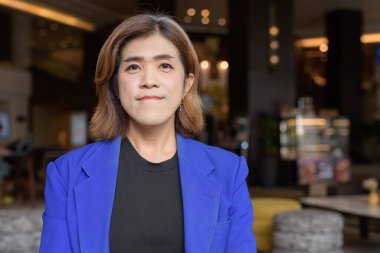 Takım elbiseli, kendine güvenen Asyalı transseksüel kadın kahve dükkanında tek başına oturuyor.