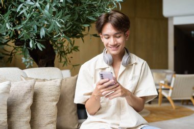 Modern kahve dükkanında oturan Asyalı yakışıklı olmayan çift yönlü öğrenci.