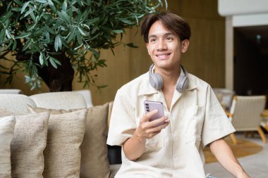 Modern kahve dükkanında oturan Asyalı yakışıklı olmayan çift yönlü öğrenci.