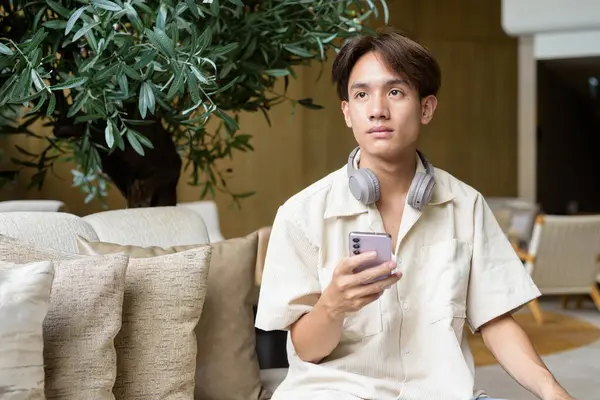 Modern kahve dükkanında oturan Asyalı yakışıklı olmayan çift yönlü öğrenci.