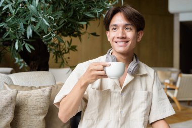 Modern kahve dükkanında oturan Asyalı yakışıklı olmayan çift yönlü öğrenci.