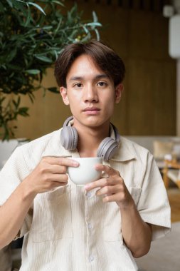 Modern kahve dükkanında oturan Asyalı yakışıklı olmayan çift yönlü öğrenci.