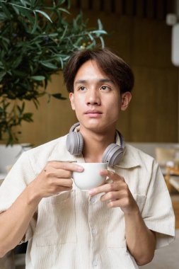 Modern kahve dükkanında oturan Asyalı yakışıklı olmayan çift yönlü öğrenci.