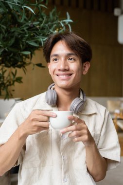 Modern kahve dükkanında oturan Asyalı yakışıklı olmayan çift yönlü öğrenci.