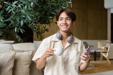 Modern kahve dükkanında oturan Asyalı yakışıklı olmayan çift yönlü öğrenci.