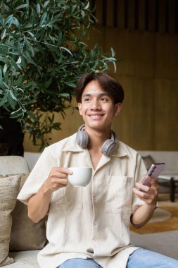 Modern kahve dükkanında oturan Asyalı yakışıklı olmayan çift yönlü öğrenci.