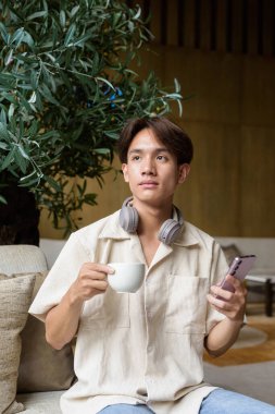 Modern kahve dükkanında oturan Asyalı yakışıklı olmayan çift yönlü öğrenci.