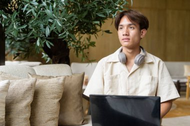 Modern kahve dükkanında oturan Asyalı yakışıklı olmayan çift yönlü öğrenci.