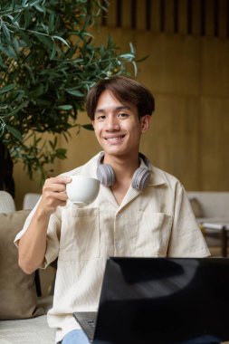 Modern kahve dükkanında oturan Asyalı yakışıklı olmayan çift yönlü öğrenci.