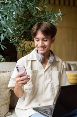 Modern kahve dükkanında oturan Asyalı yakışıklı olmayan çift yönlü öğrenci.