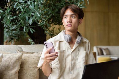 Modern kahve dükkanında oturan Asyalı yakışıklı olmayan çift yönlü öğrenci.