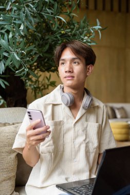 Modern kahve dükkanında oturan Asyalı yakışıklı olmayan çift yönlü öğrenci.