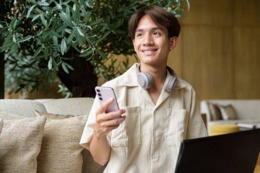 Modern kahve dükkanında oturan Asyalı yakışıklı olmayan çift yönlü öğrenci.